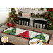 The Tree Farm Table Runner colored in red, cream, and green fabrics from the Winterly collection, staged on a rustic wood table with coordinating trees, garlands, and decor. Coordinating plates and cutlery peek into frame.