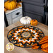 The completed topper quilt in black, white, and orange Halloween fabrics, staged on a wooden table with coordinating decor.