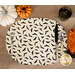 A top shot of the bat oval placemat set with silverware, surrounded by coordinating Halloween decor.