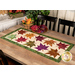 A shot of the finished runner staged on a wooden table with coordinating decor, showing all the patchwork details and fabric colors.