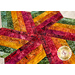 A super close up on the center of the topper, a pinwheel of bright, rich red, orange, yellow, and green as all the fabric strips meet in the middle point.