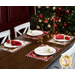 A shot of the four completed placemats displayed on a brown wooden table set with tableware and coordinating fabric napkins and decor. A decorated Christmas tree sits in the background.