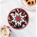 A top-down shot of the completed round hot pad in brown, staged on a marble counter with coordinating decor like cookies for Santa and a mug of hot cocoa.