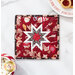 A top-down shot of the completed square hot pad in red, staged on a marble counter with coordinating decor like cookies for Santa and a mug of hot cocoa.