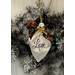 A white fabric angel ornament with Love written in script, adorned with a colorful bow, hangs on a wreath.