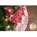 A top down shot of the tree skirt underneath a decorated Christmas tree on a dark wood grain floor.