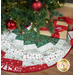 A festive quilted tree skirt with red and green patterns, placed under a decorated Christmas tree.