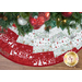 A colorful quilted Christmas tree skirt with red, green, and white patterns under a decorated tree.