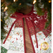 The back of a festive quilted tree skirt with red, green, and white patterns, featuring animals and greenery, tied in a red bow