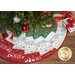 A circular Christmas tree skirt featuring red, green, and white fabric with festive patterns and animals.