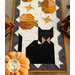 A top down shot of one end of the runner, showing a black cat with two stars and two pumpkins; a pumpkin peeks into frame from the lower left corner.