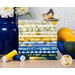 A stack of the fabric featured in the Limoncello FQ set, with lemons in a bowl and a vase and flowers and thread and a butterfly