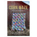 The front of the Corn Maze pattern featuring the finished quilt held up in front of a weathered barn.