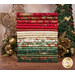 A stack of the festive fabrics included in the Good Tidings FQ set, with a tree and gold ornaments and a golden tree topper.