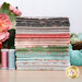 A stack of fabric samples featuring various floral and geometric patterns in soft pastel colors.