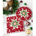 A top-down shot of the two round and square quilted hot pads slightly overlapping on a white marble counter while coordinating Christmas table decor is scattered across the counter around the hot pads.