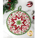 A white round quilted pot holder with a red, white, and green star pattern displayed on a white marble counter while coordinating seasonal decor peeks into the right and left sides of the frame.