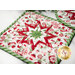 An angled close up of the white square quilted pot holder with a red, white, and green star pattern displayed on a white marble counter while the round pot holder slightly overlaps the square one from the corner of the frame.