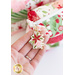 A close up on the gold-outlined acrylic poinsettia zipper pull of the charm bag. A model holds the zipper pull to demonstrate shape and color.