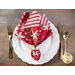 A top down shot of a place setting with the red poinsettia fabric of the napkin faced out.