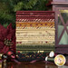 A Vintage Christmas FQ in a stack with a lantern, a flower, baubles, thread, and ribbon.