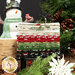 A stack of festive fabric rolls in red, green, cream, and black, with a snowman and holiday greenery in the background.