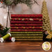 A stack of the fabrics included in the Baubles & Balsam FQ set, with coordinating holiday décor and thread.