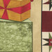 A yellow gift box with a red ribbon sits atop a green box, adjacent to a quilt-patterned fabric.