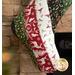 A  Christmas stocking with festive designs, hanging near a stone fireplace.