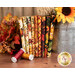 A stack of the fabrics included in the Autumn Fields FQ Set, with a jug and flowers and thread.
