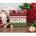 A stack of fabrics from the Santa's Coming to Town collection, with a sleigh and houses and Santa and ornaments and thread.