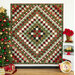 A diamond-patterned quilt in red, green, and white is displayed near a Christmas tree and decorations.