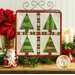 The completed Foundation Paper Piecing Series 2 project for December, an arrangement of four dynamic Christmas trees in red, green, and white fabrics, staged on a rustic wooden tabletop from a craft stand with coordinating decor.