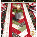 A narrow close up shot of the table runner with a candle as its centerpiece, cloth napkins laid on white plates peeking into the frame on each side.