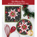 Two completed versions of the black Folded Star Hot Pads, staged on a white marble countertop with coordinating decor like garlands and baking utensils.