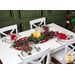 The completed table runner colored in black, red, and green gnome fabrics, on a white table staged with coordinating plates, glassware, cloth napkins, and candles nestled in greenery.