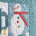 An angled close up on one of the snowman blocks, demonstrating fabric, piecing, embellishment, and stitching details.