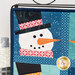 A close up on the upper left snowman, demonstrating fabric, piecing, laser shape, and top stitching details.