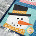 A super close up on one of the snowmen, showing fabric, piecing, laser shape, and top stitching details as a silver garland peeks into frame.