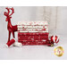 A stack of the fabrics featured in the Nordic Noel FQ set, with a Deer statue and trees and ornaments and thread.