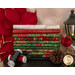 A stack of the fabrics included in the Joyful collection, with a lampost and a Cardinal and a poinsetta and pinecones and thread.