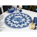 A shot of the completed Point of View Folded Star Table Topper Kit in fabrics from the Holiday Flourish - Festive Finery collection, a series of wintry blue metallic prints. It is staged on a white table with coordinating blue and winter decor.