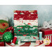 A stack of Christmas fabrics with ornaments and a gingerbread cookie plush and presents and peppermints and thread.