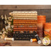 A stack of fat quarters from the bundle in warm autumn colors, staged with spools of thread and decorative candles.
