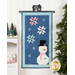 The completed Sweet Snowman door banner, colored in icy and wintry blue, white, and pink fabrics, hung on a white paneled wall and staged with coordinating winter decor.