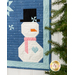 A close up on the snowman, showing fabric and piecing details; a pine tree peeks into frame from the right side.