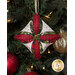 A head on shot of one of the ornaments, colored in white, olive, and scarlet fabrics, staged on a Christmas tree.