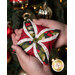 A model holds one of the ornaments before a lit and decorated Christmas tree.