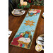 A stylized shot of the completed Star of Wonder Table Runner colored in rich blue, red, yellow, and green fabrics, staged on a rustic wooden table among four coordinating table settings and holiday decor.