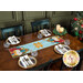 The completed Star of Wonder Table Runner colored in rich blue, red, yellow, and green fabrics, staged on a rustic wooden table among four coordinating table settings and holiday decor.